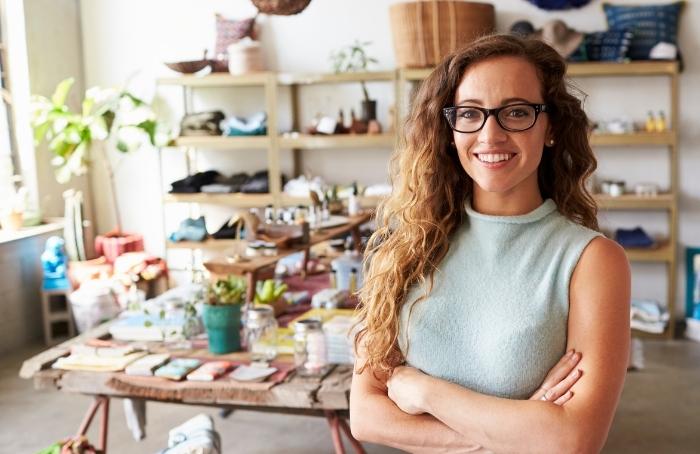 La dueña de un negocio sonríe en su tienda después de usar una buena deuda para hacer crecer su negocio
